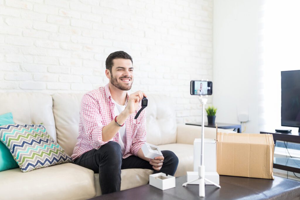 A man creates a product demo video for a smartwatch using his camera phone on a tripod on top of his coffee table.