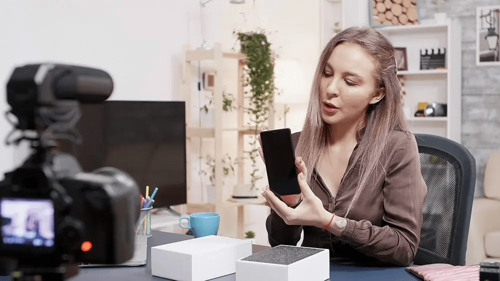 A woman presents a smartphone, which are some of the most popular and best unboxing videos in electronics.